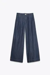 Pantalón de jean azul oscuro, corte wide leg, tiro alto con pinzas delanteras, bolsillos laterales y cierre frontal con cremallera y botón.