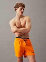Bañador corto naranja con cintura elástica y cordón, confeccionado en 100% poliéster reciclado.