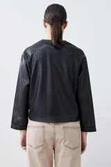 Chaqueta negra de eco cuero calado, con cuello redondo y cierre frontal con botones a presión.