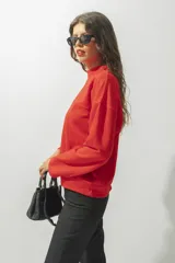 Buzo rojo de corte holgado con cuello redondo y mangas largas. Presenta una costura horizontal en el pecho y bordado con el nombre de la marca.