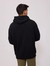 Canguro negro con capucha y cordones blancos, bolsillo tipo canguro y logo de la marca estampado en el pecho.