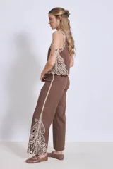 Pantalón blanco de corte ancho con bordados calados en forma de hojas en el ruedo.