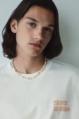 Remera blanca de algodón de corte holgado con estampado del artista Keith Haring en el pecho. Modelo de H&M con cuello redondo y mangas cortas.