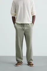 Pantalón color arena de corte recto, confeccionado en tejido de algodón y lino. Cuenta con cintura elástica ajustable con cordón, bolsillos delanteros y traseros de parche.