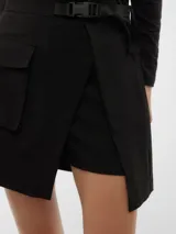 Minifalda negra con diseño cruzado, cinturón con hebilla y bolsillo lateral con solapa.
