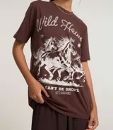 Remera blanca de algodón con cuello redondo y mangas cortas. Estampa frontal con diseño western de caballos y texto "Wild Heart".