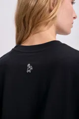 Remera negra de corte recto con estampa frontal con la frase "Rue de Magique" en letras blancas.