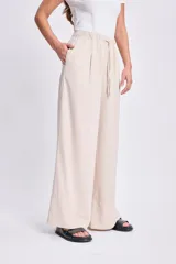 Pantalón de lino color beige, de corte palazzo, con cintura elastizada y cordón ajustable.