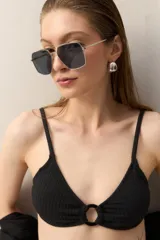 Top de bikini negro con textura, breteles finos y aro metálico en el centro del busto.