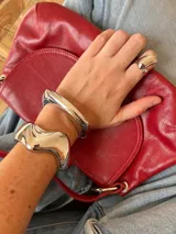 Brazalete rígido plateado con diseño irregular y anillo a juego.