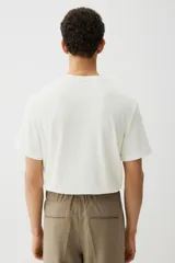 Remera blanca de punto texturizado de peso medio, corte estándar, cuello redondo y mangas cortas.