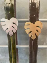 Cinto de cuero charolado, ancho 3 cm, con hebilla de metal en forma de hoja.