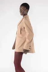 Blazer color beige de corte holgado con solapas y cierre con dos botones.
