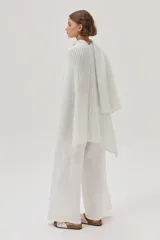 Ruana beige de tejido de punto acanalado con mangas cortas.