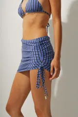 Minifalda de playa con estampado a rayas verticales azules y negras, con cordones laterales ajustables.