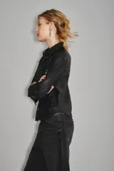 Camisa de cuero ovino color negro, de corte jeanero, con bolsillos tipo ojal en el delantero y cierre frontal con broches a presión con el logo de Rapsodia.