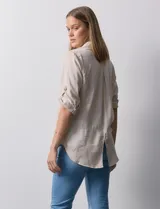Camisa color beige de tencel, marca Hester & Orchand. Cuello con solapa, escote en V y abertura central con botones. Delantera con bolsillos. Largo de manga regulable con presilla y botón.