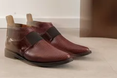 Bota corta color borgoña con textura de reptil, puntera fina, elástico negro en el empeine y talón descubierto.