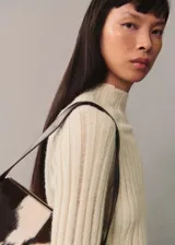Sweater de punto color crema con cuello perkins y diseño de canalé vertical con aberturas.
