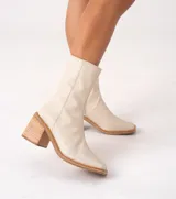 Bota corta color crema con textura de reptil, caña media, punta cuadrada, cierre lateral y taco de madera.
