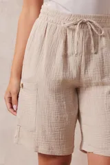 Bermuda de algodón color beige, marca Robert Louis, con pretina ancha elastizada con lazo de ajuste simulado, bolsillos verticales delanteros y bolsillos laterales con botón.