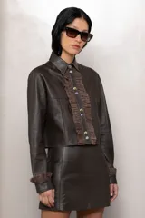 Minifalda marrón de cuero, con corte ajustado y tres hebillas metálicas al frente.