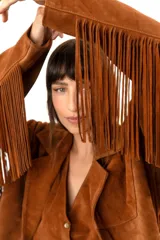 Blazer marrón de gamuza con flecos en la espalda y mangas largas.