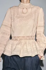 Camisa color crema de algodón con cuello alto, manga larga con puños con volantes y bordados a tono.