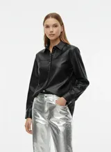 Camisa negra de manga larga con efecto cuero y acabado brillante. Presenta cuello clásico, cierre frontal de botones y puños abotonados. El diseño incluye un ligero volumen en las mangas.