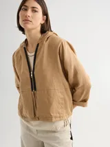 Chaqueta color marrón claro de lino, con capucha, cierre frontal con cremallera negra y bolsillos laterales. Corte holgado. Diseñada y fabricada en Uruguay.