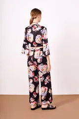 Conjunto de pantalón y top de viscosa con estampado floral en tonos rosa, celeste, amarillo y rojo sobre fondo negro. El top es cruzado con mangas acampanadas y el pantalón es de corte palazzo con cintura elastizada.