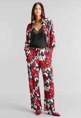 Pantalón pijamero de satén calado estampado con diseño floral en rojo, blanco y negro. Calce relajado, cintura elastizada y bolsillos ocultos.