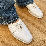 Zuecos negros de cuero con punta cuadrada y detalle de nudo en el empeine.