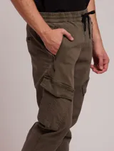 Pantalón cargo color ocre de sarga, con cintura elástica ajustable con cordón, bolsillos laterales con cierre y bolsillos cargo con solapa en los muslos.