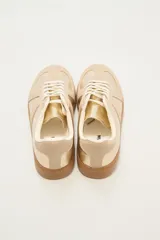 Zapatillas deportivas color beige y dorado con suela marrón.