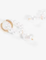Aros decorativos en tono plateado con detalles de perlas, diseñados para aportar un toque elegante.