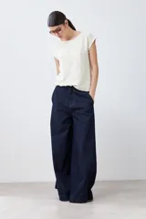 Blusa color beige con textura de lunares en relieve, cuello redondo y mangas cortas.