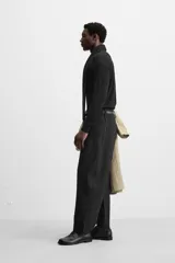 Pantalón negro de corte amplio tipo balloon fit, con cintura con pliegues frontales, bolsillos delanteros y traseros de plastrón. Cierre frontal con cremallera y botón.