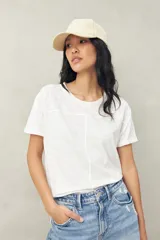 Remera blanca de manga corta confeccionada en algodón liviano con textura levemente jaspeada. Presenta tajos laterales y costura central al frente.