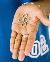 Par de aros plateados con forma de flor de cuatro pétalos, cada uno con una estrella esmaltada en azul y rojo.