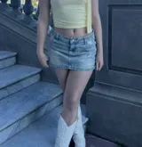 Minifalda de jean celeste con efecto lavado, tiro bajo y bolsillos delanteros y traseros.