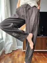 Pantalón de lino color marrón topo, de corte amplio, con cintura elastizada ajustable con cordón, bolsillos laterales y un bolsillo tipo cargo en la pierna derecha.