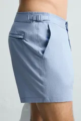 Short de baño celeste de tejido técnico con cintura elástica ajustable con cordón interior y trabillas laterales. Tiene bolsillos frontales y bolsillo trasero con cierre de cremallera. Cuenta con forro interior y cierre frontal con cremallera y botón a presión oculto.