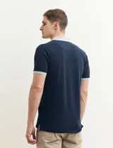 Remera polo blanca de piqué con cuello y puños en azul marino. Tiene tapeta de dos botones y bolsillo de parche en el pecho.