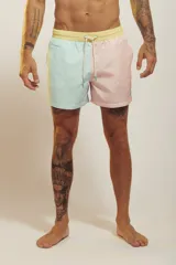 Short de baño para hombre, tiro medio, con estampado tropical en tonos rosados, verdes y blancos. Posee cintura elástica con cordón de ajuste trenzado y bolsillos laterales.