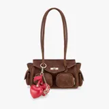 Bolso tipo satchel de gamuza color marrón, con dos bolsillos frontales con cierre y un bolsillo lateral con solapa. Cierre principal con broche metálico y dos asas de hombro delgadas. Incluye un charm colgante de cuero rojo con forma de cereza y un dije metálico dorado.