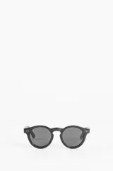 Lentes de sol negros con montura redonda y detalles de remaches en los laterales.
