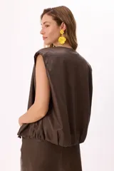 Chaleco negro de símil cuero suave con botones a presión y ruedo regulable.