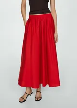 Falda midi roja de corte evasé con diseño de tablas y cierre de cremallera invisible en el lateral.