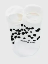 Calcetín invisible de algodón blanco con estampado de manchas negras en la planta del pie y la palabra "puppies" escrita en negro.